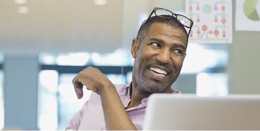 Man smiling whilst looking at a computer